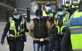 Police detain a protester (c) at a proposed anti-lockdown rally which failed to materialize in Melbourne on August 9, 2020.