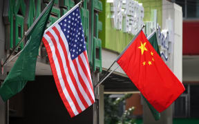 The US (L) and Chinese flags are displayed outside a hotel in Beijing on May 14, 2019. - Beijing's latest retaliation against US tariff hikes -- an increase on $60 billion of US imports from June 1 -- could leave China running low on ammunition in the trade war. (Photo by Greg Baker / AFP)