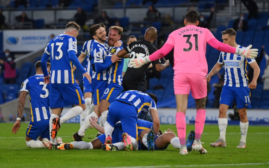 Brighton's English defender Dan Burn is mobbed by teammates after scoring their third goal during the English Premier League football match between Brighton and Hove Albion and Manchester City at the American Express Community Stadium in Brighton, southern England on May 18, 2021.