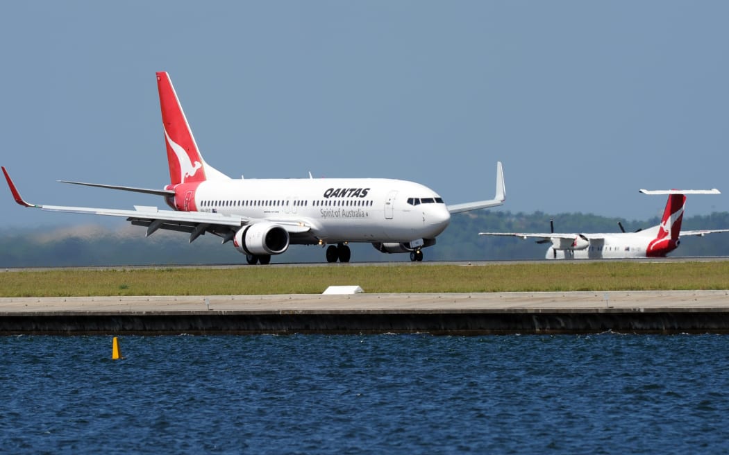 A Qantas Boeing 737, left,lands as a Qantas Q-400, right, prepares to take off at Sydney International Airport in November 2011.