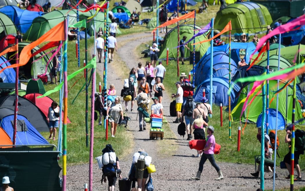 Festivalgoers arrive to attend the Glastonbury festival in the village of Pilton, in Somerset, South West England, on June 22, 2022. - More than 200,000 music fans and megastars Paul McCartney, Billie Eilish and Kendrick Lamar descend on the English countryside this week as Glastonbury Festival returns after a three-year hiatus. The festival takes place from June 22 to June 26, 2022. (Photo by ANDY BUCHANAN / AFP)