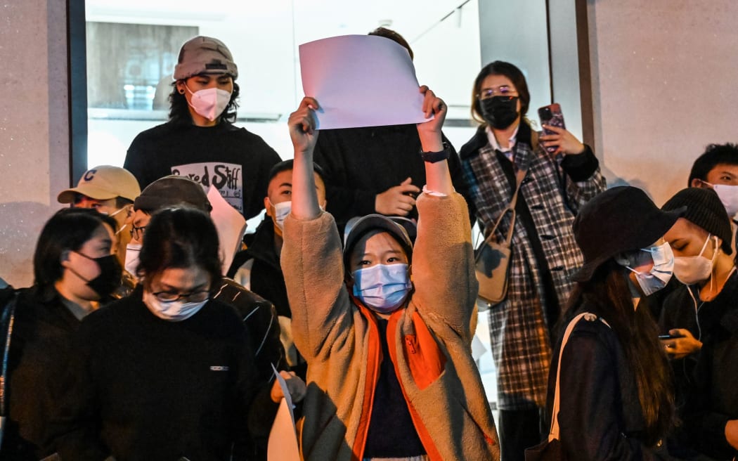 People hold up blank papers as a way to protest against China's strict Covid measures while gathering on a street in Shanghai on 27 November, 2022.