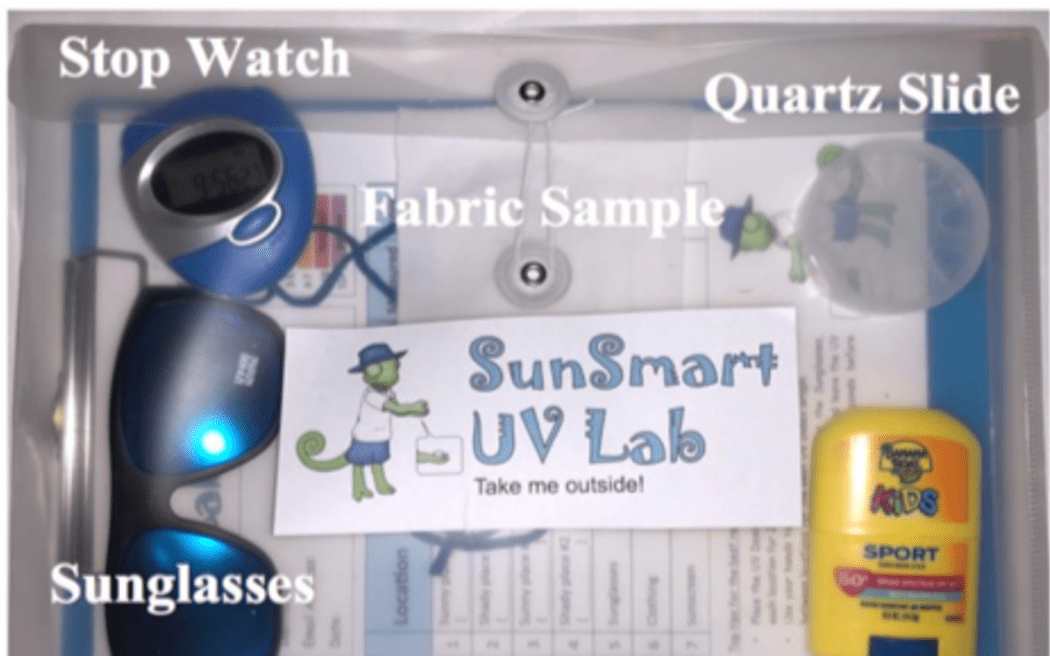 A container with a dosimeter, sunglasses, clipboard, sunscreen and a piece of paper labelled 'SunSmart UV lab: Take me outside!'