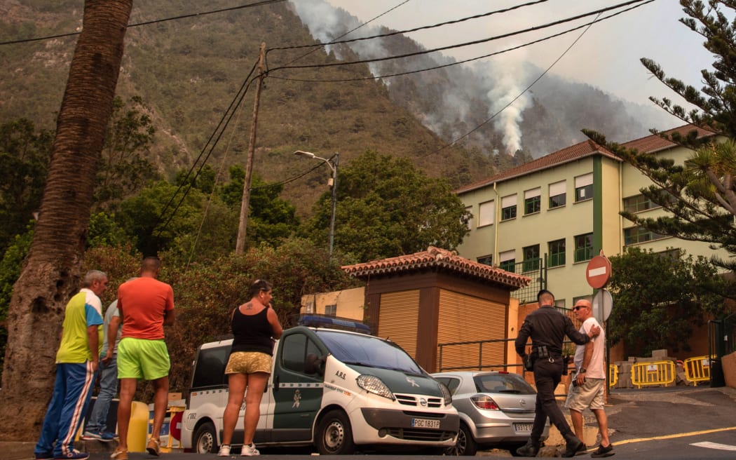 Un guardia civil habla con los residentes de La Orotava mientras un incendio forestal se descontrola en las laderas boscosas de la isla canaria de Tenerife, el 19 de agosto de 2023. Es posible que más de 26,000 personas se hayan visto obligadas a huir de un incendio forestal masivo que se ha extendido desde control en el país, dijeron hoy los servicios de emergencia en la isla española de Tenerife.  El incendio forestal, que estalló el martes por la noche en una zona montañosa en el noreste de la isla, es "El incendio más complejo" Las Islas Canarias atlánticas de España se han visto afectadas en más de 40 años, dicen las autoridades.  (Foto de Desiree Martin/AFP)