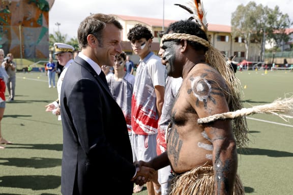 French President Emmanuel Macron shakes hands with a traditional dancer during a visit to the Magenta suburb of Noumea.