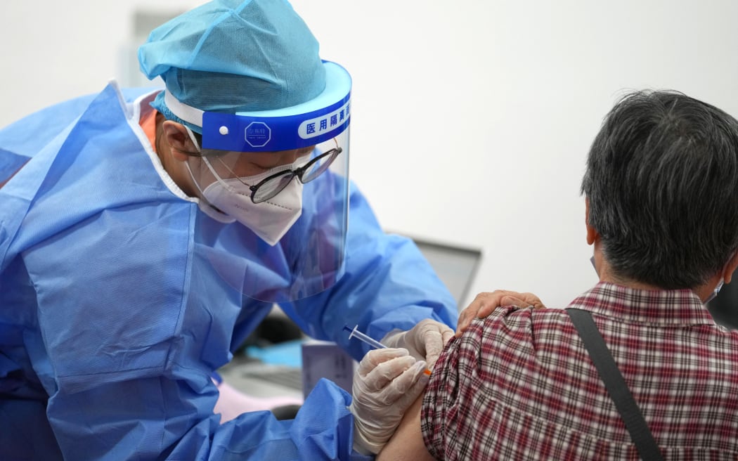 (221217) -- BEIJING, Dec. 17, 2022 (Xinhua) -- A medical worker injects a booster shot of COVID-19 vaccine for a resident at Aoyuncun Subdistrict in Chaoyang District, Beijing, capital of China, July 13, 2022. (Xinhua/Ju Huanzong) (Photo by Ju Huanzong / XINHUA / Xinhua via AFP)