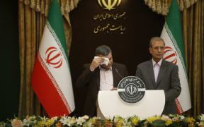 Iranian Deputy Health Minister Iraj Harirchi, left, wipes his brow during a media conference.