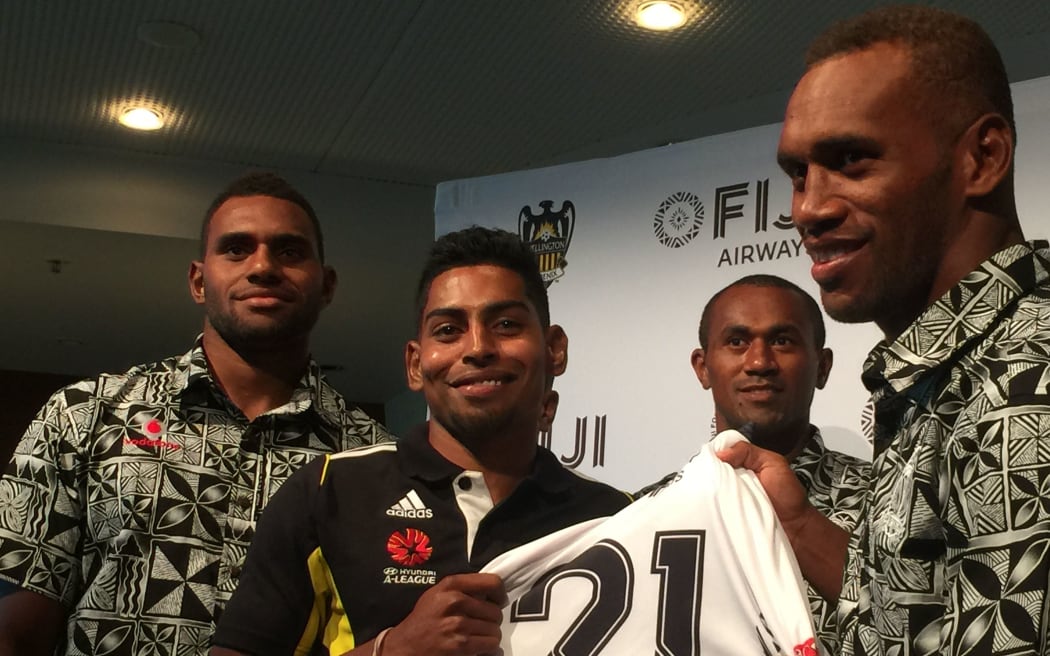 Wellington Phoenix striker Roy Krishna is presented with a jersey by the Fiji rugby sevens team.