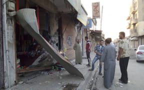People inspect a shop damaged after what Islamist State militants say was a US drone crashed into a communication station in Raqqa.