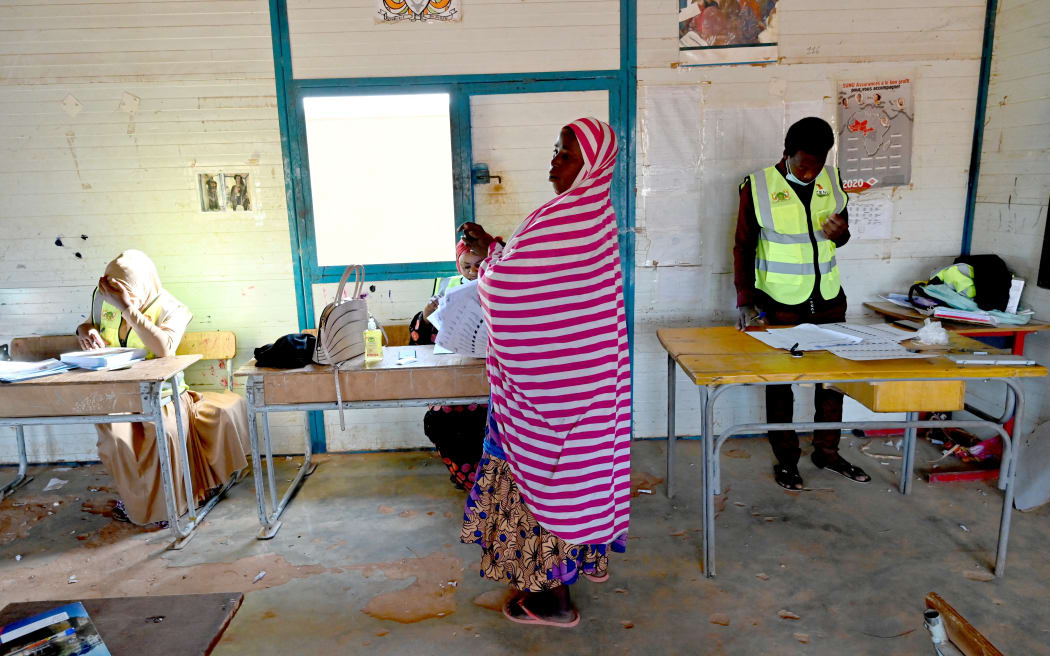 A woman waits to cast her vote in a classroom at a polling station in Niamey on 21 February, 2021 during Niger's second round of the presidential election.