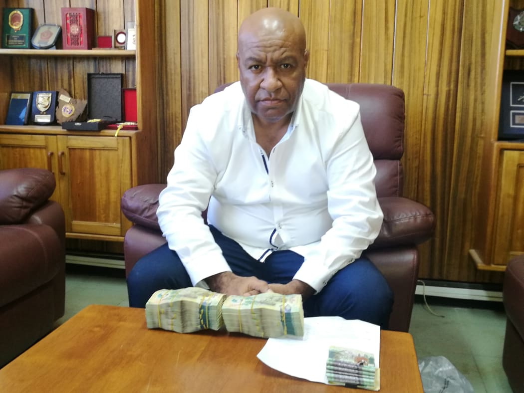 Senior Sergeant Apollo Terry with the K100,000 kina cash bribe. On the right of the picture is the K6,500 cash found on policeman.