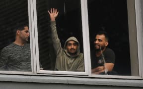 Asylum seekers gesture to protesters holding a pro-refugee rights rally from their hotel room where they have been detained in Melbourne on June 13, 2020, after they were evacuated to Australia for medical reasons from offshore detention centres on Nauru and Manus Island. (Photo by William WEST / AFP)