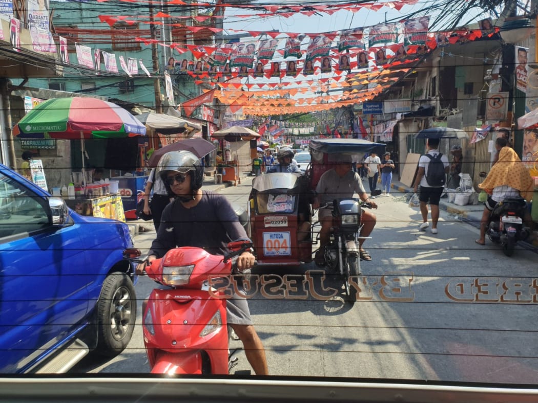 busy street scene in Manila with mopeds and street stalls.