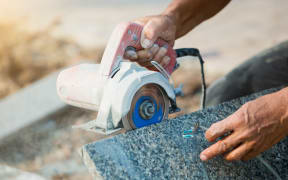 worker cutting granite stone with an diamond electric saw blade and use water to prevent dust and heat at a construction site