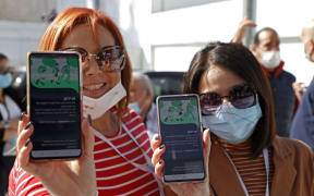 Attendees show off their "green passes" (proof of being fully vaccinated against COVID-19 coronavirus disease) as they arrive at Bloomfield Stadium in the Israeli Mediterranean coastal city of Tel Aviv on March 5, 2021, before attending a "green pass concert" for vaccinated seniors.