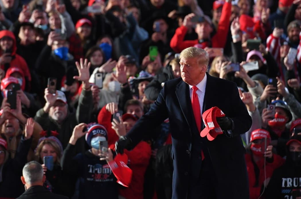 US President Donald Trump throws MAGA hats to supporters as he arrives for a rally at Pittsburgh-Butler Regional Airport in Butler, Pennsylvania on October 31, 2020. (Photo by MANDEL NGAN / AFP)