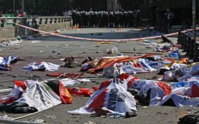 Turkish riot police forces secure the site of twin explosions. Victims' bodies are covered with banners and flags, Ankara, October 10, 2015.